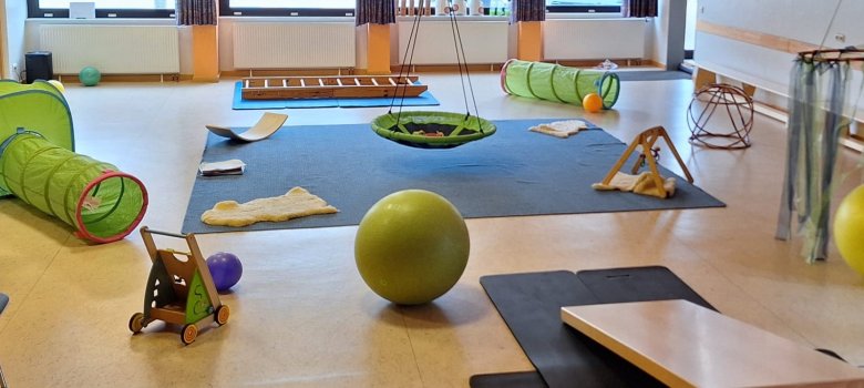 Kinderspielraum mit buntem Spielzeug – Tunnel, Hängematte, Ball und Klettergerüst